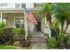 Inviting front porch with brick steps, colorful flowers, and an American flag creating a warm welcome at 7003 Cupseed Ln, Harmony, FL 34773