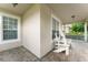 Cozy porch with brick flooring, windows, and white chairs, perfect for relaxation and enjoying the outdoors at 7003 Cupseed Ln, Harmony, FL 34773