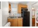 Functional kitchenette with wooden cabinets, black fridge, microwave, and sink, maximizing space at 7003 Cupseed Ln, Harmony, FL 34773