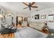 Bright living room featuring wood floors, ceiling fan, and neutral-toned couches and chair at 7003 Cupseed Ln, Harmony, FL 34773