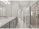 Bright bathroom featuring double vanities, a glass-enclosed shower, and neutral tile flooring at 7724 Sweet Star Ave, Orlando, FL 32836