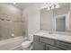 Bathroom with tub and shower has a gray vanity with quartz countertop, and tiled walls at 7724 Sweet Star Ave, Orlando, FL 32836