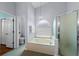 Bright bathroom featuring a soaking tub under an arched window and a glass-enclosed shower at 824 Spring Island Way, Orlando, FL 32828