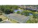 Aerial shot of well-maintained tennis courts next to a tranquil lake in a lush, green community at 824 Spring Island Way, Orlando, FL 32828
