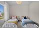 Cozy bedroom with two twin beds featuring soft decor and warm natural light from a window at 10829 Royal Cypress Way, Orlando, FL 32836