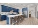 Modern kitchen featuring blue cabinets, stainless steel appliances, a large island with seating, and wood-look tile flooring at 10829 Royal Cypress Way, Orlando, FL 32836