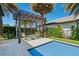 Inviting pool area with a pergola-covered seating area, palm trees, and manicured landscaping for relaxation and entertainment at 10829 Royal Cypress Way, Orlando, FL 32836