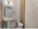 Stylish powder room featuring patterned wallpaper, a modern pedestal sink, and elegant gold fixtures at 10829 Royal Cypress Way, Orlando, FL 32836