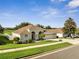 Well-manicured single-story home featuring a three-car garage, lush green lawn, and mature trees at 10955 Lemay Dr, Clermont, FL 34711