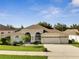 Beautiful single-story home with a three-car garage, landscaped front yard, and well-maintained lawn at 10955 Lemay Dr, Clermont, FL 34711
