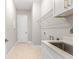 Functional laundry room with utility sink, white cabinets, and convenient shelving for storage at 1257 Champions Dr, Daytona Beach, FL 32124