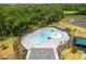 An aerial view showcases the community pool surrounded by lush greenery and comfortable lounge chairs at 1267 Berry Ln, Davenport, FL 33837