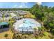 An aerial view of the community pool, lush landscaping, and neighboring homes on a bright, sunny day at 1267 Berry Ln, Davenport, FL 33837