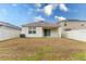 A view of the backyard, highlighting the lawn, a patio, privacy fence and the home's back exterior at 1267 Berry Ln, Davenport, FL 33837
