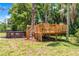 Inviting backyard featuring mature trees, a wooden deck play area, and a refreshing above-ground pool at 174 Pine Grove Ct, Daytona Beach, FL 32119