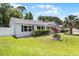 Corner view of a delightful white brick home featuring a decorative wishing well and lush green lawn at 174 Pine Grove Ct, Daytona Beach, FL 32119