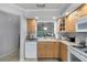 Cozy kitchen features wood cabinets, white appliances, and a pass-through window to the dining area at 179 Crown Point Cir, Longwood, FL 32779