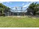 Spacious backyard featuring a screened in pool enclosure, set against a backdrop of lush greenery and lake views at 1962 English Dr, Deltona, FL 32738