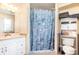The charming bathroom features seashell shower curtain, vanity, and a practical shelving unit for storage at 1962 English Dr, Deltona, FL 32738