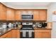 A kitchen with wood cabinets, mosaic backsplash, stainless steel microwave, and electric range at 1962 English Dr, Deltona, FL 32738