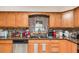 A kitchen with wood cabinets, stainless steel dishwasher, mosaic backsplash and stainless steel sink at 1962 English Dr, Deltona, FL 32738