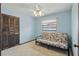 Cozy bedroom with light blue walls, window, closet, and a floral futon couch at 2028 Lake Christie Dr, Orlando, FL 32809