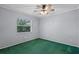 Simple bedroom with a ceiling fan, window overlooking greenery, and green carpet at 216 San Fernando Ct, Sanford, FL 32773