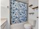 This bathroom features a tub with a floral shower curtain, shelves, and a toilet at 2227 Doulton Dr, Orlando, FL 32812