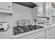 Close-up featuring stainless steel stove top, stylish white backsplash, and complementary white cabinets at 2233 Antilles Club Dr, Kissimmee, FL 34747
