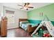 Cozy bedroom with wood floors, a ceiling fan, a bright green accent wall, and tent with toys at 2850 Pewter Mist Ct, Oviedo, FL 32765