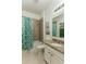 Well-lit bathroom featuring a tiled shower with a decorative leafy green curtain and a granite countertop at 410 E Victoria Trails Blvd, Deland, FL 32724