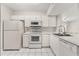 Cozy kitchen with white cabinets, appliances, and a pass-through window to the living room at 527 Villa Del Sol Cir # 104, Orlando, FL 32824