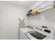 Bright laundry room with modern washer and dryer, shelving, and ironing board at 558 Cadiz Loop, Davenport, FL 33837