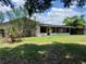 View of the back of the home with a screened in patio and overgrown lawn at 5918 Stratton Ln, Orlando, FL 32808