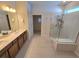 Bright bathroom featuring double sinks, a glass-enclosed shower, and neutral tile flooring at 6129 Citrus Grove Ct, St Cloud, FL 34771