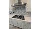 Close-up of a modern gas cooktop with a stainless steel vent hood and quartz countertops at 6129 Citrus Grove Ct, St Cloud, FL 34771