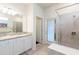 Well-lit bathroom featuring white cabinets, granite countertops, and a glass-enclosed shower at 7352 Oakmoss Loop, Davenport, FL 33837