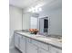 Bright bathroom with double sink vanity, granite countertops, and a large mirror at 7352 Oakmoss Loop, Davenport, FL 33837