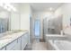 Luxurious bathroom with double vanity, soaking tub, and glass-enclosed shower for a spa-like experience at 7352 Oakmoss Loop, Davenport, FL 33837