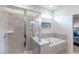 Bright bathroom showcasing a bathtub and separate glass-enclosed shower with neutral tile surround at 7352 Oakmoss Loop, Davenport, FL 33837
