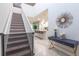Bright entryway with modern decor, featuring a staircase, stylish console table, and a glimpse of the open kitchen at 7352 Oakmoss Loop, Davenport, FL 33837