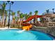 Fun water slide flowing into the pool with tropical landscaping and palm trees at 7577 Oak Spring Ln, Davenport, FL 33837