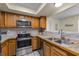 Kitchen featuring wood cabinets, tile countertops, a stainless steel sink, and modern appliances at 8121 Via Bonita, Sanford, FL 32771