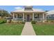 Inviting home featuring a covered front porch, fresh green lawn, neatly manicured landscaping, and patriotic American flag at 106 Turtle Run, Umatilla, FL 32784