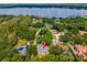 Aerial view of a home near a lake, identified by a red pin, surrounded by lush green trees and other residences at 1202 Marshall Ct, Eustis, FL 32726