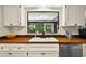Kitchen sink area featuring white cabinets and butcher block countertops with a scenic backyard view at 1202 Marshall Ct, Eustis, FL 32726