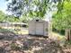 A storage shed provides practical space in the backyard, complemented by lush foliage and a sunny pergola at 1233 Gladstone Dr, Deltona, FL 32725