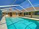 Backyard pool with a screened enclosure and adjacent to the brick home with many windows at 1233 Gladstone Dr, Deltona, FL 32725