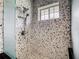 Walk-in shower with decorative pebble tile surround, rainfall shower head, and window at 1233 Gladstone Dr, Deltona, FL 32725