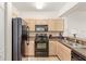 Functional kitchen with black appliances and light wood cabinetry at 12837 Madison Pointe Cir # 206, Orlando, FL 32821
